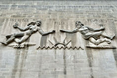 A carving with the Latin words "veritas," "filia," and "temporis" on the exterior of a limestone building.